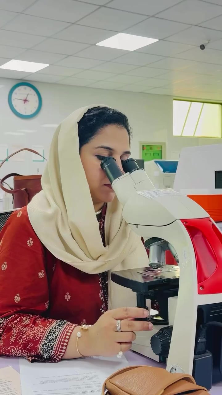 Dr Sadaf Zahid examining a slide through a microscope